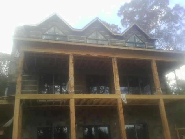 Dormers and porch framing on a large log home under construction — Roof Coating work by our crew in Evanston