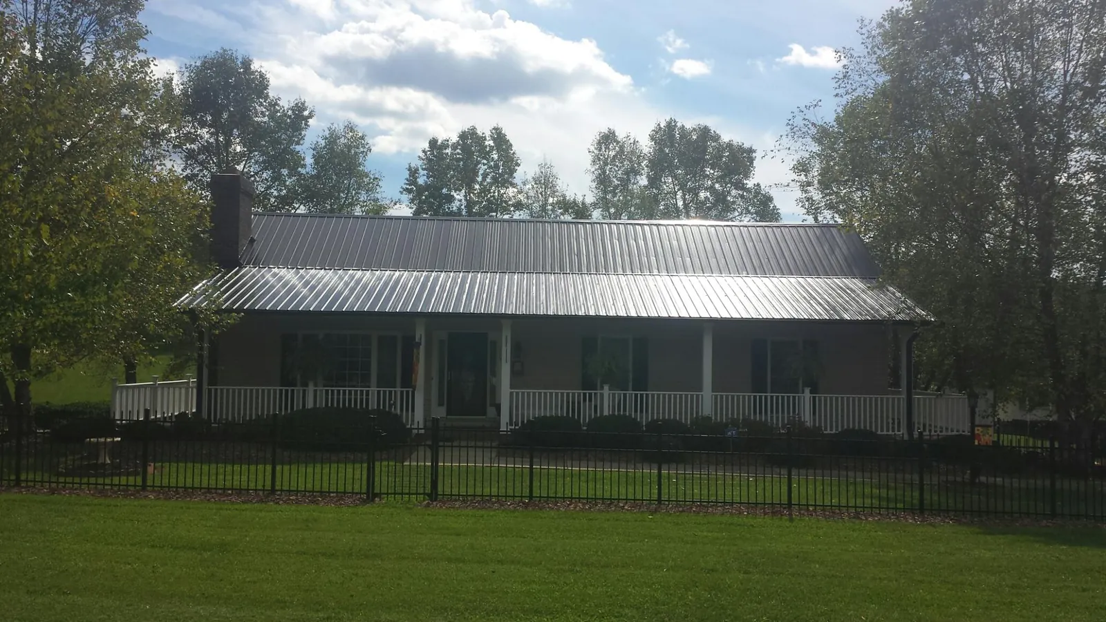 Gray metal roof on a brick ranch with a full width front porch — Gutter Guard Installation work by our crew in Evanston